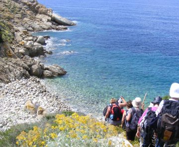 Paysage de bord de mer, avec un groupe de randonneurs qui descendent vers la plage