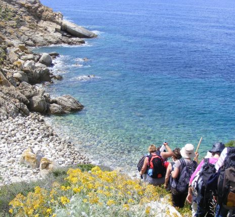 Paysage de bord de mer, avec un groupe de randonneurs qui descendent vers la plage