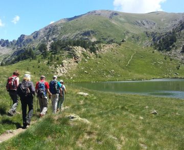 Randonneurs sur un sentier se dirigeant vers un lac, lors d'une randonnée en Andorre.