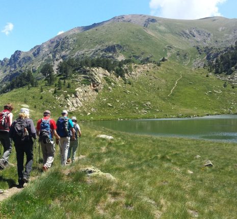 Randonneurs sur un sentier se dirigeant vers un lac, lors d'une randonnée en Andorre.