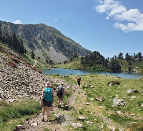 Groupe de randonneurs sur un sentier qui se dirigent vers un lac de montagne