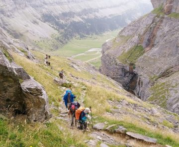 Groupes de randonneurs sur un sentier avec leur guide sur la haute randonnée pyrénéenne entre le Vignemale et les Posets