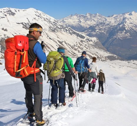 Groupe de randonneurs sur un sentier avec leur guide, en face d'eaux des sommets des hautes Pyrénées