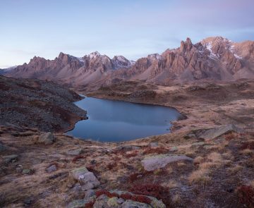Paysage de montagne dans la vallée de l'Ubaye avec un ciel et une lumière rosée due au coucher ou lever du soleil, avec un lac en contrebas