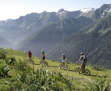 Paysage montagnard avec une famille accompagnée d'un guide en train de faire une activité en trottinette en montagne