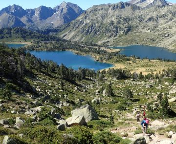 Paysage montagnard avec des lacs en contrebas, entouré de verdure, avec des sommets à l'arrière-plan