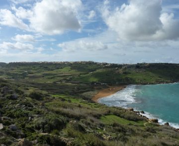Paysage côtier à Malte avec une plage et de l'eau turquoise qui sort du lot, encadré par de grandes forêts