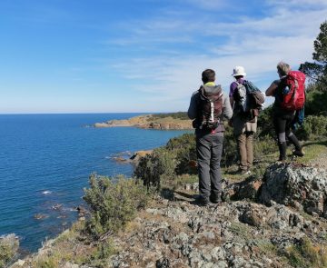 Groupe de randonneurs face à la vue de la mer sur leur chemin de randonnée