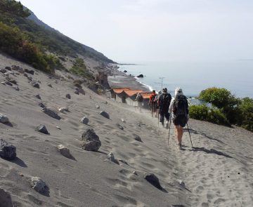 Grope de randonneurs en crète sur un sentier de sable avec la mer sur le côté