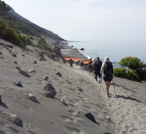 Grope de randonneurs en crète sur un sentier de sable avec la mer sur le côté