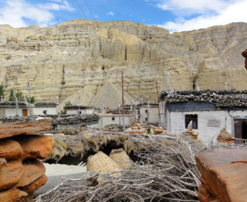 Paysage dans la zone du Mustang au Népal, avec des habitations ainsi que des roches de couleurs orangées