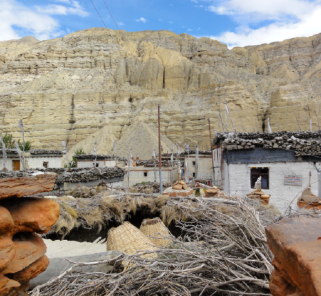 Paysage dans la zone du Mustang au Népal, avec des habitations ainsi que des roches de couleurs orangées