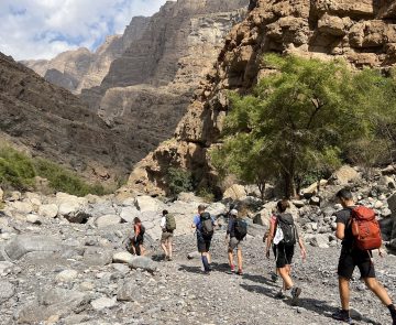 Groupe de randonneurs avec leur guide sur un sentier de pierre à travers les montagnes d'Oman