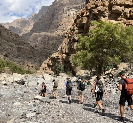 Groupe de randonneurs avec leur guide sur un sentier de pierre à travers les montagnes d'Oman