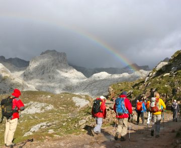 groupe de randonneurs sur un sentier dans les picos de europa avec des sommets enneigés en arrière-plan