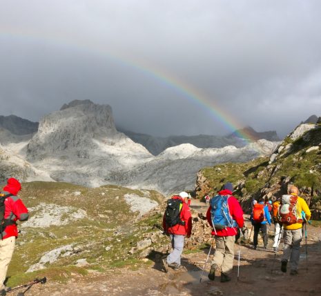 groupe de randonneurs sur un sentier dans les picos de europa avec des sommets enneigés en arrière-plan