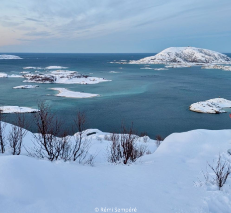 Uns personne regarde l'horizon sur de la neige au bord de l'eau