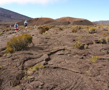 Paysage de la réunion avec un groupe de randonneurs qui marche sur des terres volcaniques