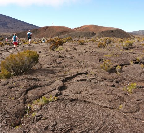 Paysage de la réunion avec un groupe de randonneurs qui marche sur des terres volcaniques