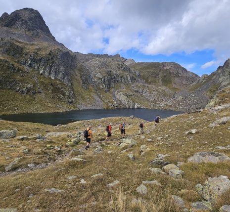 groupe de randonneurs s'avançant sur un sentier avec leur guide dans le massif des Posets, avec un lac en contrebas et des sommets